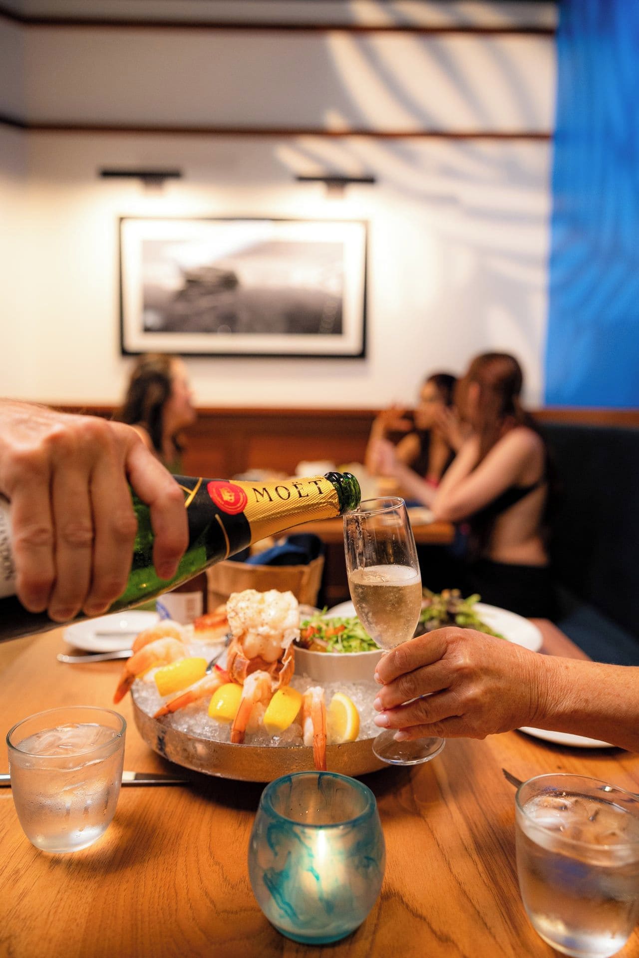 A dining table with seafood, a bottle of champagne, and glasses.
