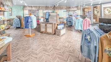 Un magasin de vêtements doté d’un plancher en bois, d’un comptoir de caisse et de différents présentoirs à vêtements.