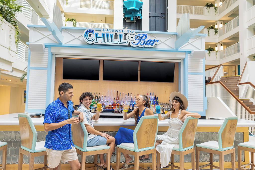A bar area with a sign reading 'LICENSE TO CHILL BAR' and a group of people seated at the bar.