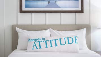 Uma cama com um travesseiro que diz “Mudanças de Atitude” e um quadro com uma imagem de um cais que leva a uma paisagem nevada.