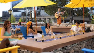 Zona de bar con asientos al aire libre y escenario para música en vivo.