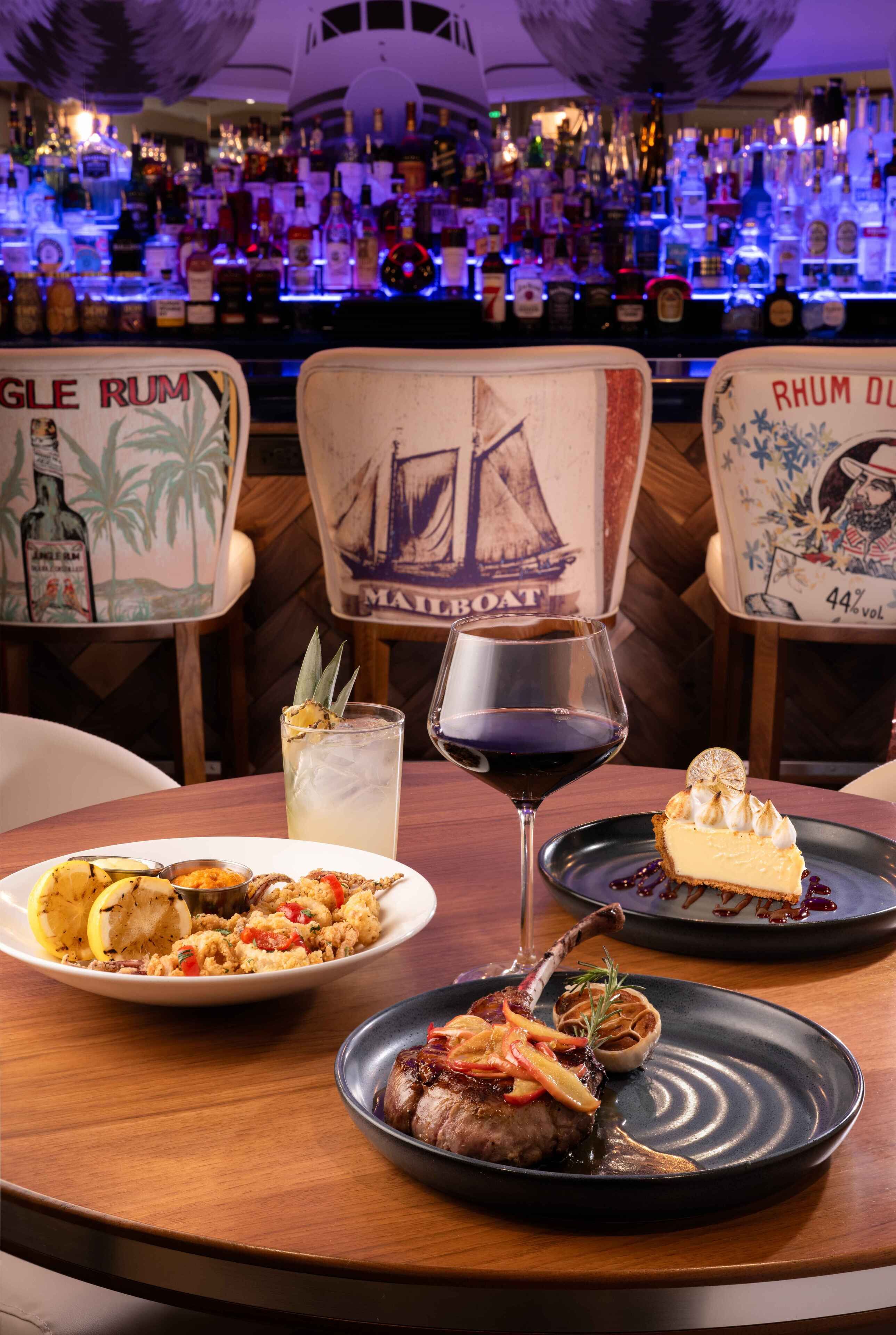 A bar area with a variety of liquor bottles, a glass of red wine, and a plate of food.