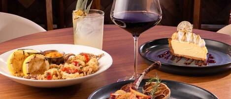 A bar area with a variety of liquor bottles, a glass of red wine, and a plate of food.