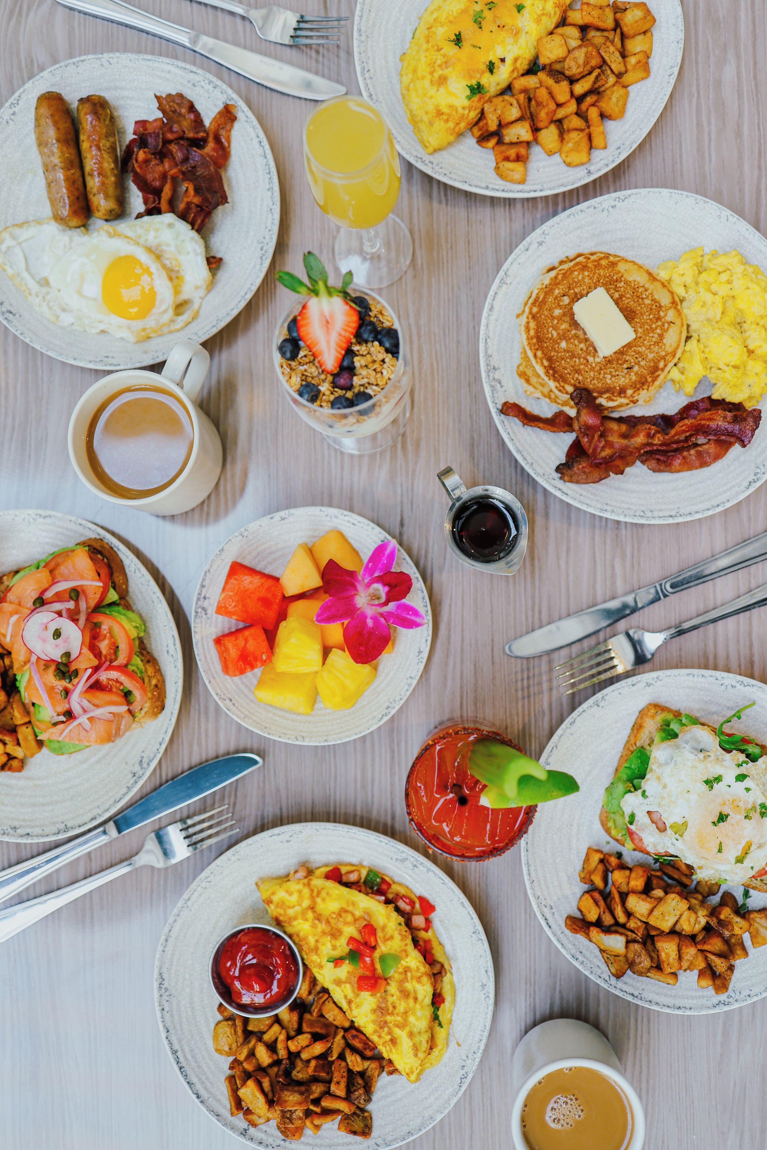 Un buffet de petit-déjeuner proposant divers plats, notamment des œufs, du bacon, des saucisses et des fruits.