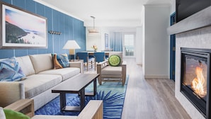 A modern living room with a fireplace, blue accent walls, a sofa, a coffee table, and a view of the outdoors. - Margaritaville Resort Lake Tahoe (South Lake Tahoe)