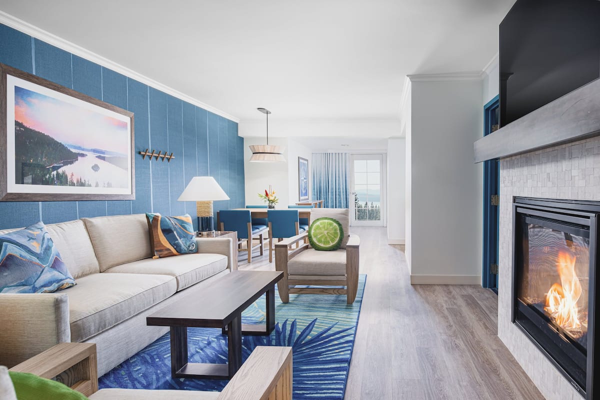 A modern living room with a fireplace, blue accent walls, a sofa, a coffee table, and a view of the outdoors.