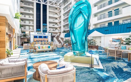 A spacious indoor lobby with a large blue sculpture, comfortable seating areas, and a view of the upper floors.