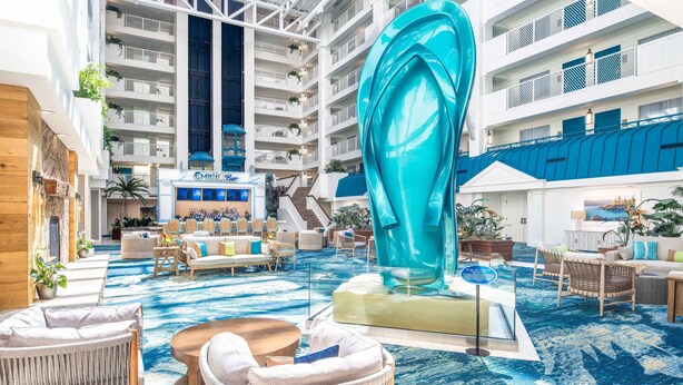A spacious indoor lobby with a large blue sculpture, comfortable seating areas, and a view of the upper floors.