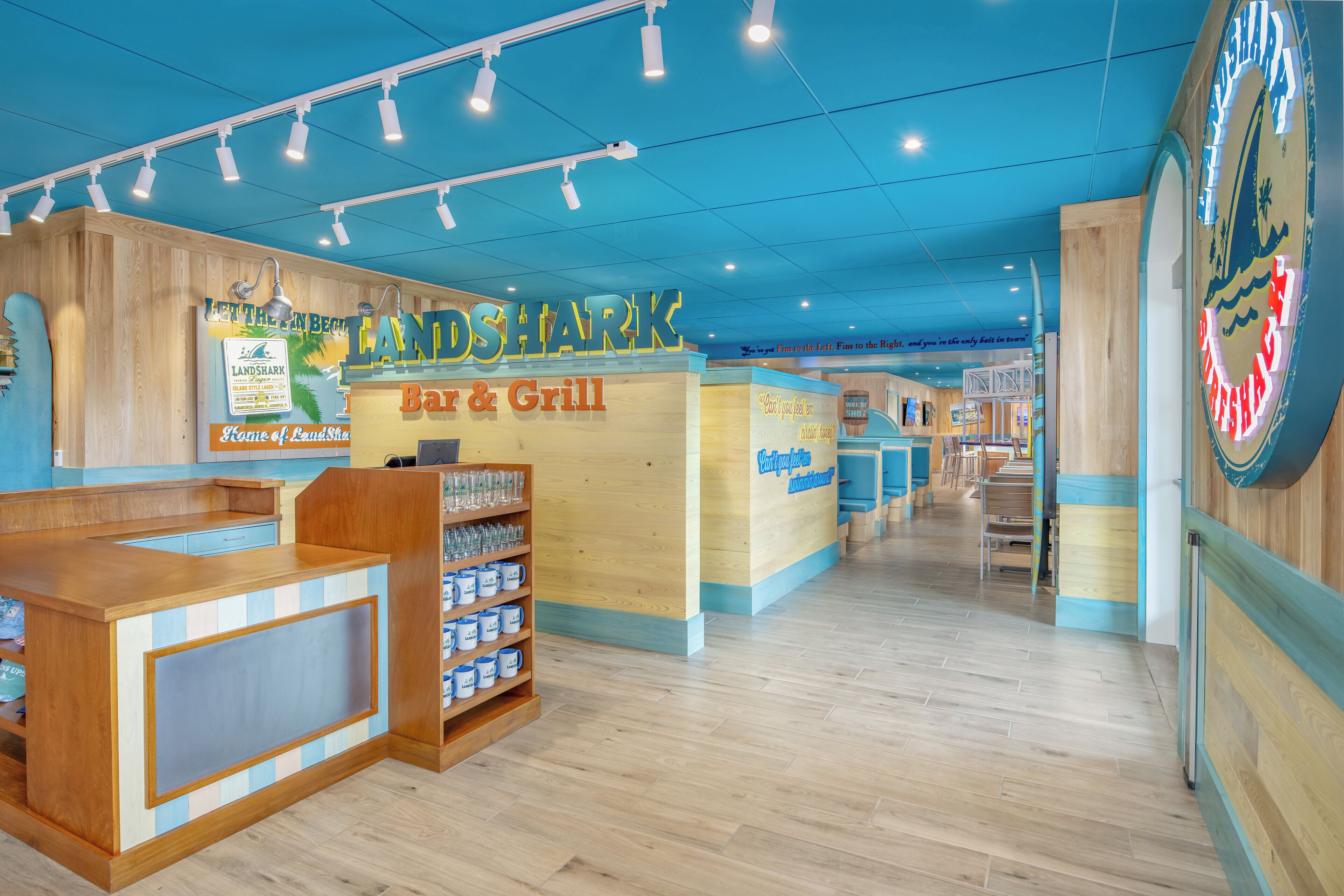 A restaurant interior with a 'Land Shark Bar & Grill' sign, wooden counter, and blue and white checkered floor.