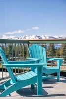 Two turquoise Adirondack chairs on a balcony with a mountain view.