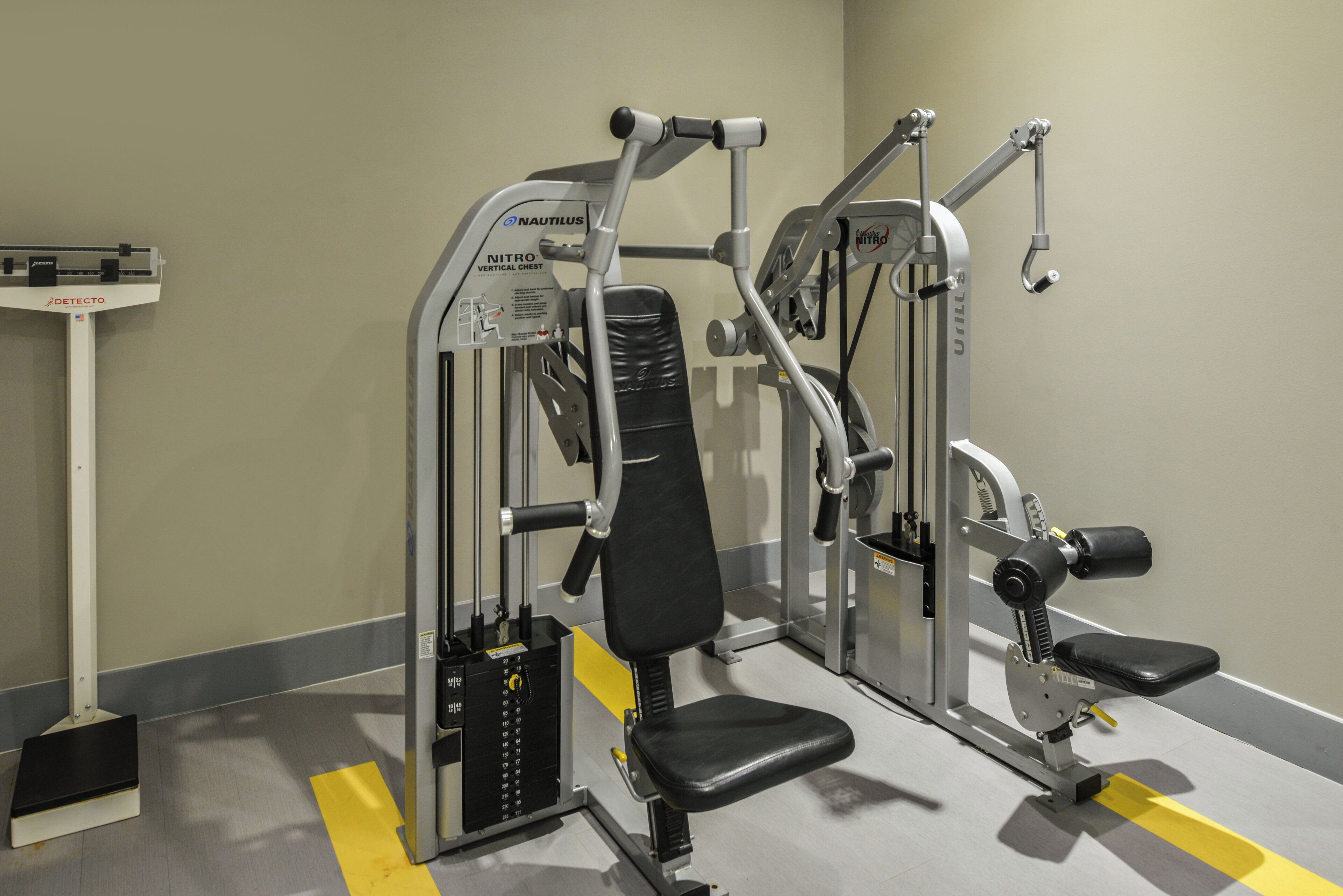 Ein Fitnessraum mit Nautilus- und Detecto-Geräten, einer Hantelbank und einem Squat-Gestell.