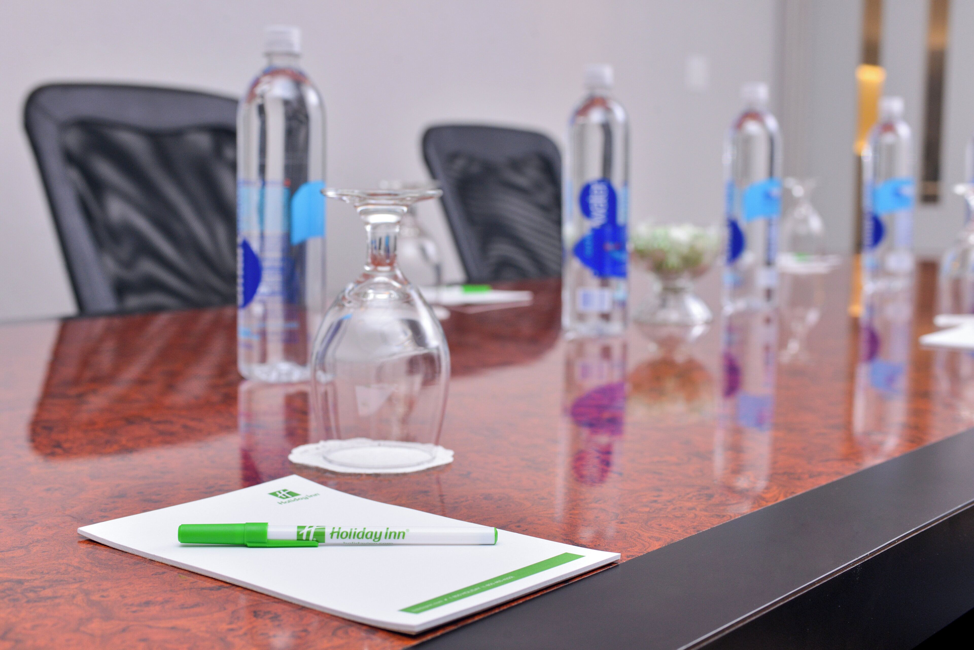 Una mesa de conferencias con un bloc de notas, bolígrafos y botellas de agua.