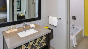 A bathroom with a sink, mirror, and bathtub.