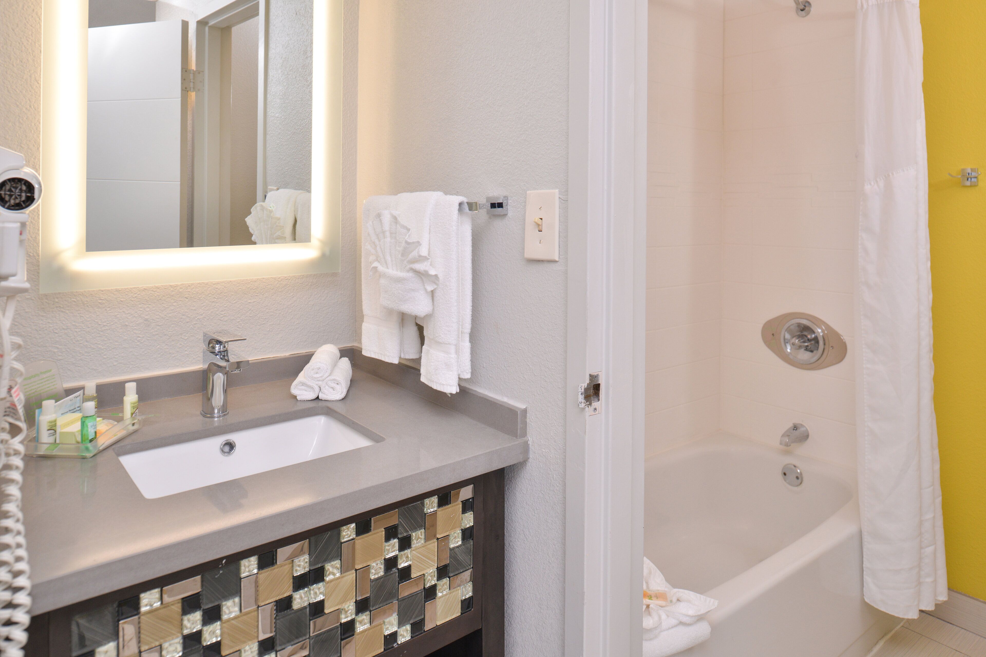 A bathroom with a sink, mirror, and shower.