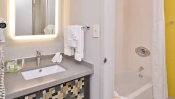 A bathroom with a sink, mirror, and shower.