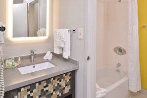 A bathroom with a sink, mirror, and shower.