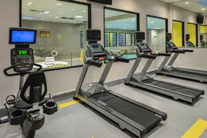 Un centre de remise en forme équipé de tapis de course, d’appareils d’exercice et d’un écran numérique.