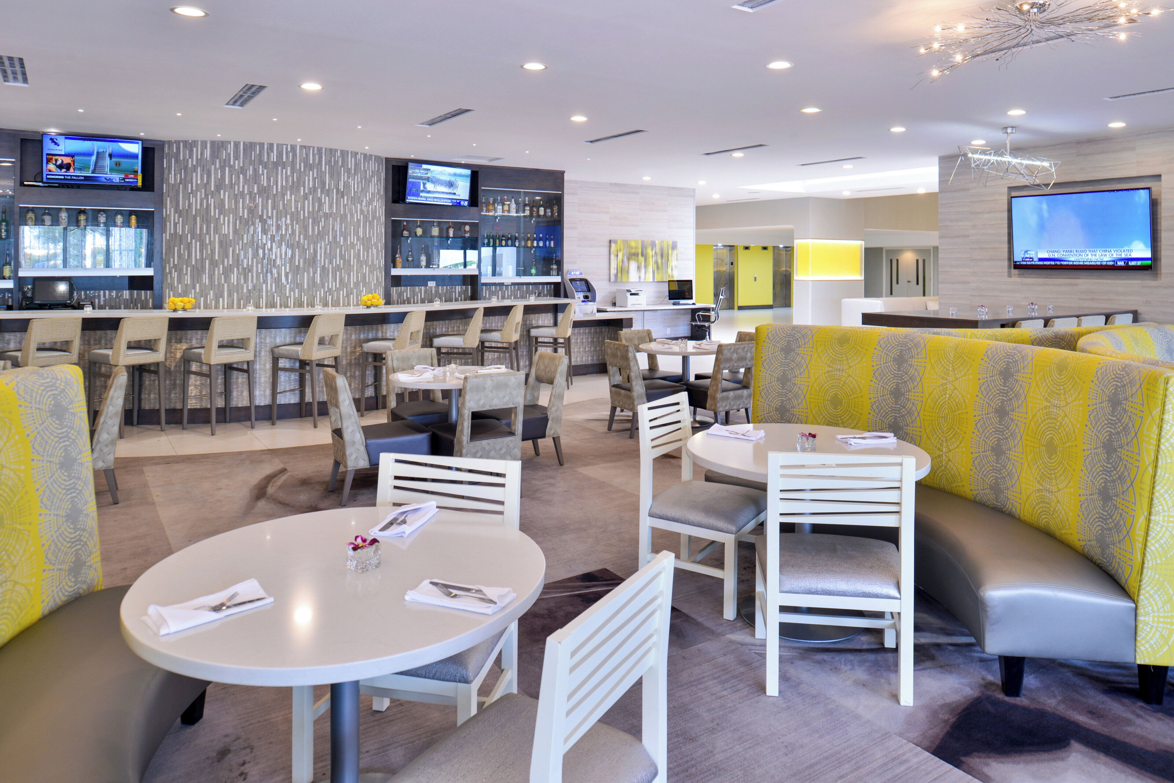 A modern restaurant with a bar area, seating arrangements, and a television screen.