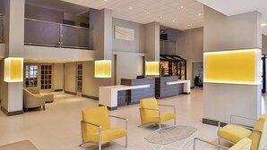 A spacious lobby with a reception desk, seating area, and a staircase leading to an upper level.