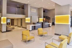 A spacious lobby with a reception desk, seating area, and a staircase leading to an upper level.