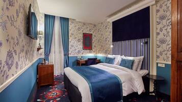 A bedroom with a bed, a desk, a chair, a TV, and a nightstand.
