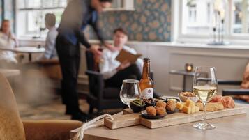 Un comedor con una mesa dispuesta para una comida, incluyendo pan, queso y una botella de vino.