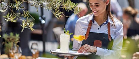 A person serving a drink with a lemon wedge on a tray.