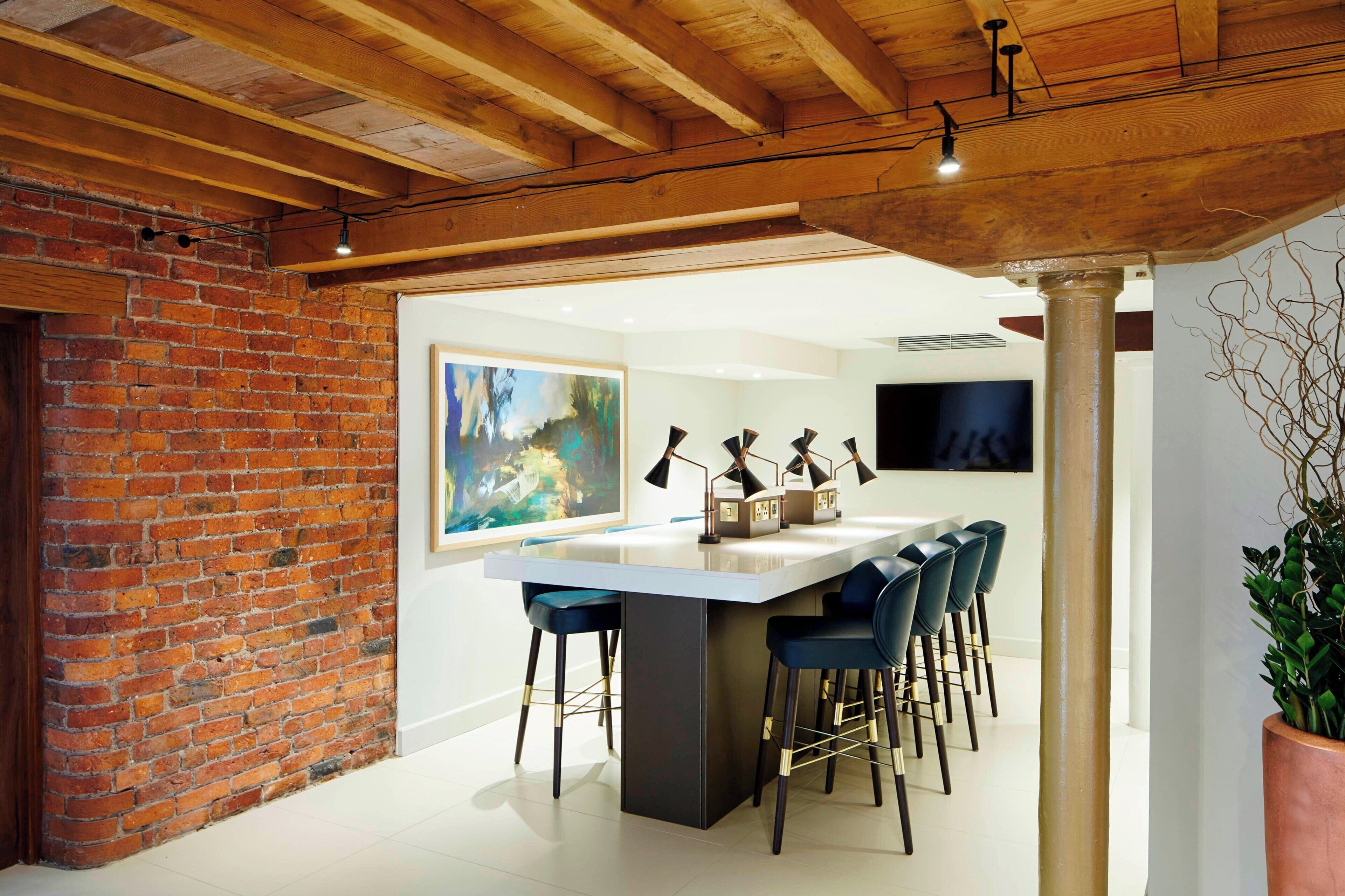 Een moderne keuken met een groot eiland, barkrukken en een bakstenen muur.
