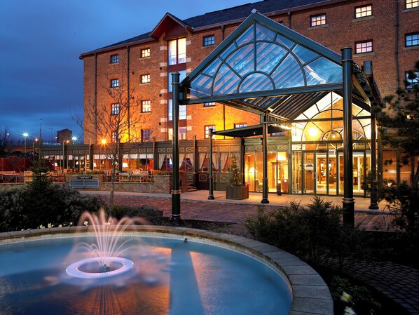 A hotel with a glass-roofed entrance, a fountain, and a brick building facade. - Manchester Marriott Victoria & Albert Hotel (Manchester)