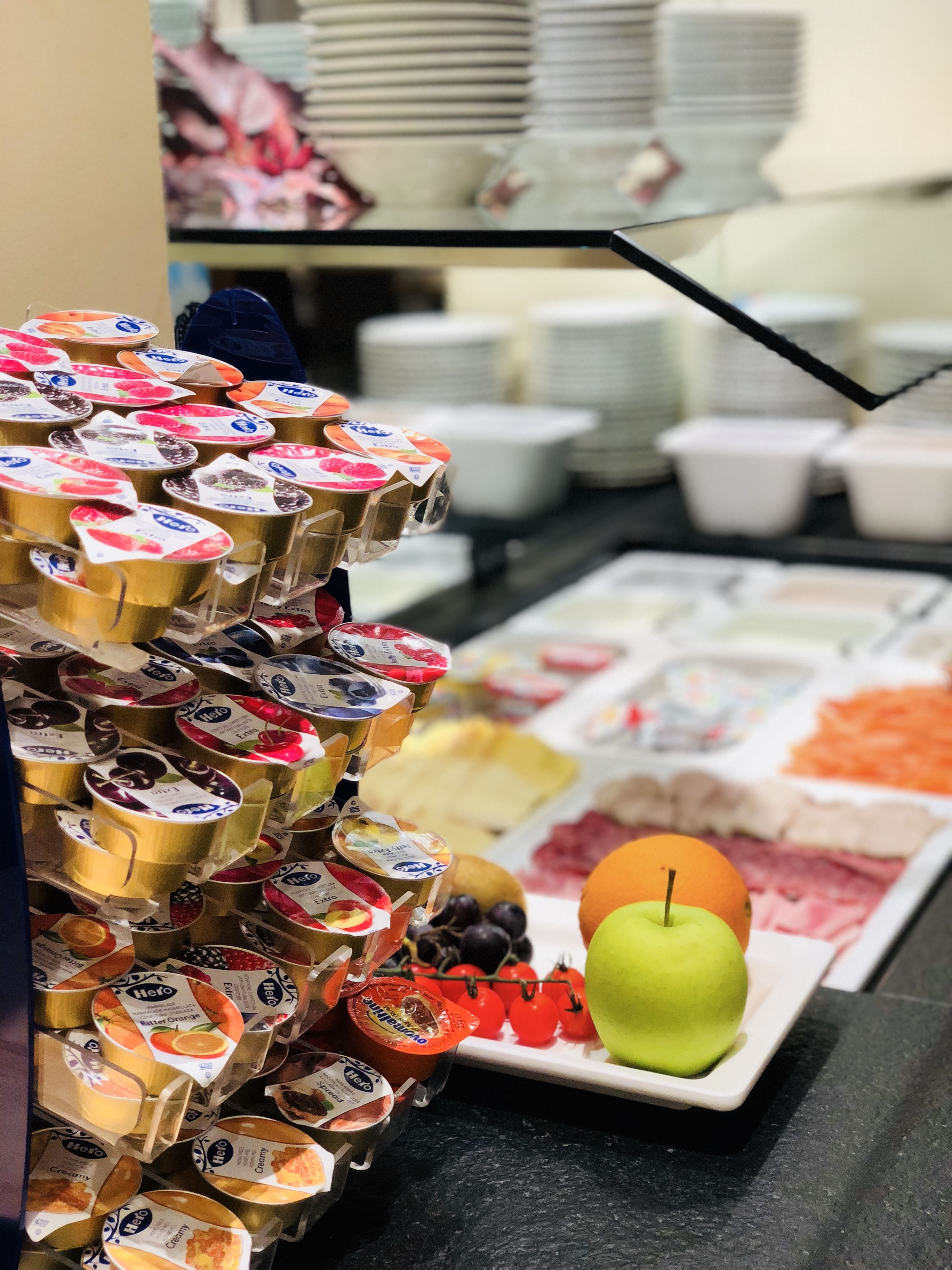 A buffet with various food items including yogurt, fruits, and a green apple.