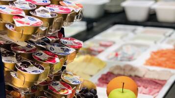Un bufé con diversos alimentos, incluyendo yogur, frutas y una manzana verde.