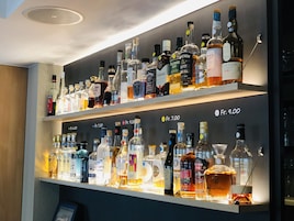 Un bar con numerosas estanterías llenas de botellas de licores, cada una con su precio indicado.