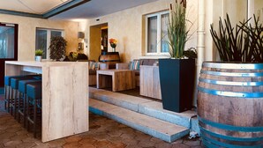A modern interior with a wooden reception desk, seating area, and a large planter with tall plants. - Hotel Felmis (Horw)