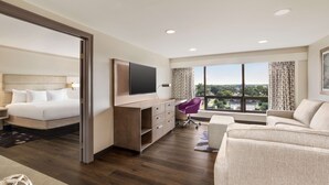 Una habitación de hotel moderna con una cama, un escritorio con una silla, un sofá y un amplio ventanal con vistas a la ciudad.