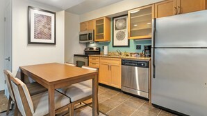 A modern kitchen with wooden cabinets, a stainless steel refrigerator, a microwave, and a dishwasher. - MainStay Suites St. Louis - Galleria (Richmond Heights)