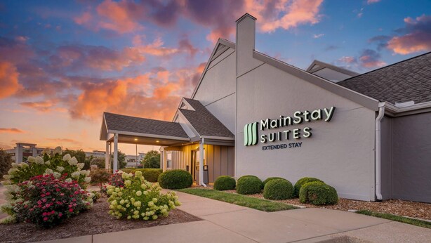 A MainStay Suites building with a covered entrance, landscaped garden, and a clear sky. - MainStay Suites St. Louis - Galleria (Richmond Heights)