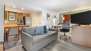 A modern apartment with a kitchenette, a sofa, a desk, and a TV. - MainStay Suites St. Louis - Galleria (Richmond Heights)
