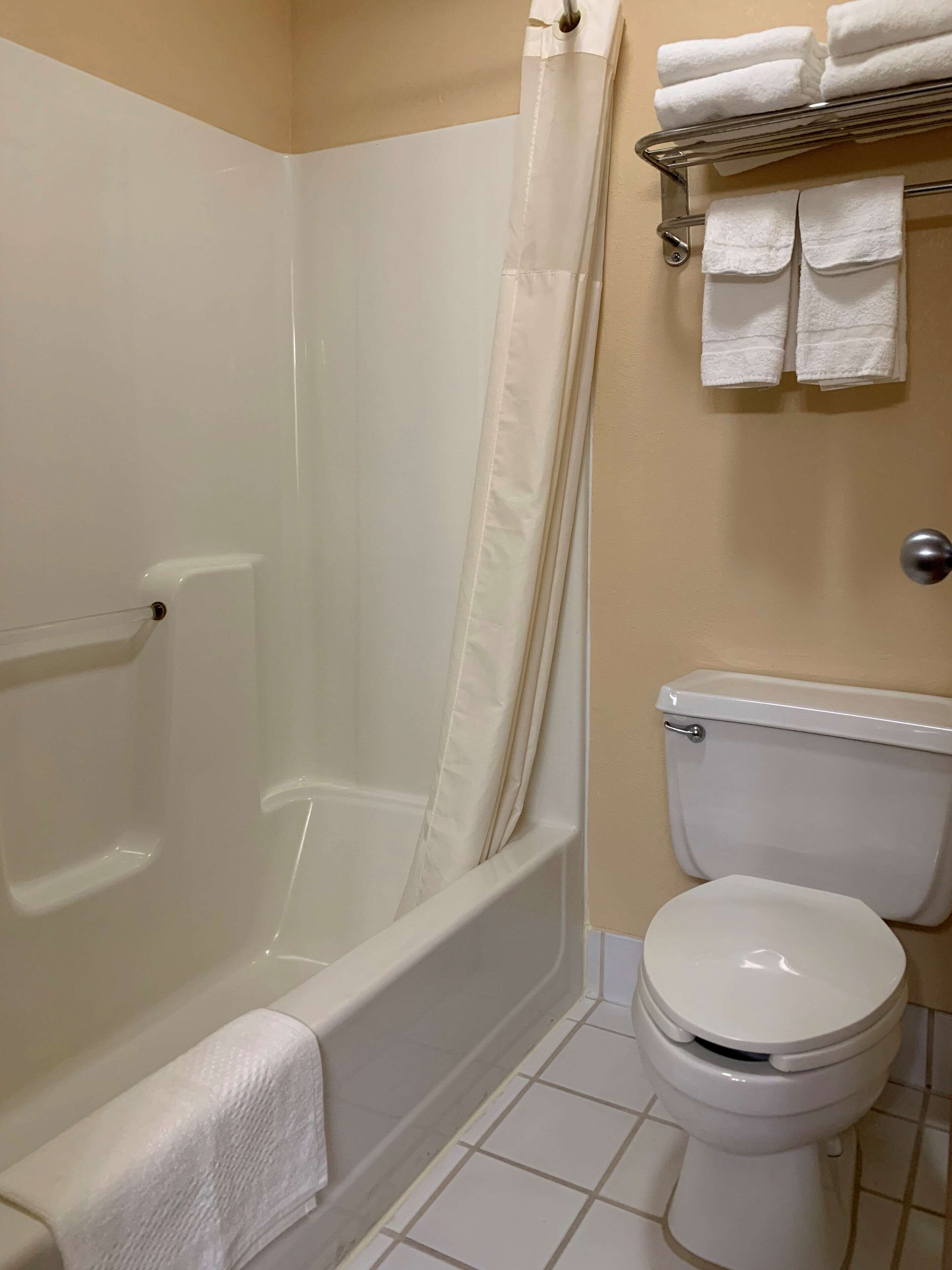 Un baño con bañera, inodoro y toallero con toallas dobladas.