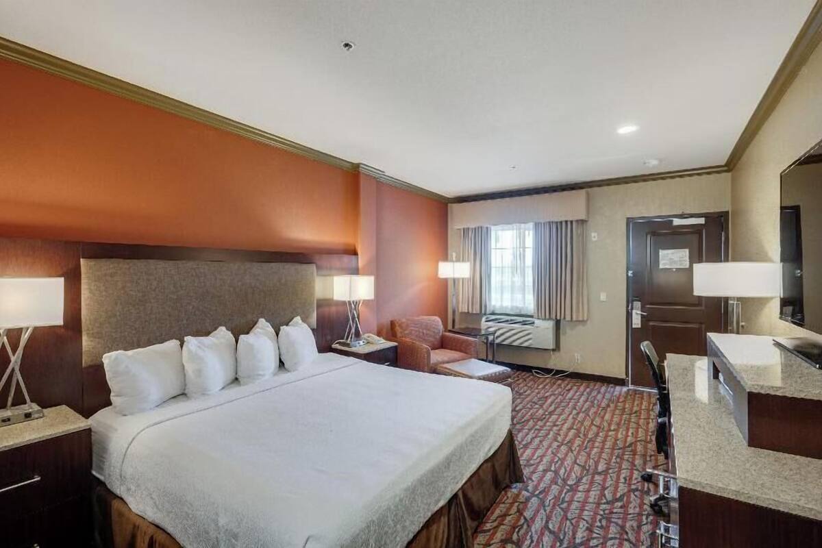 A hotel room with a large bed, a desk, a chair, a TV, and a bathroom.