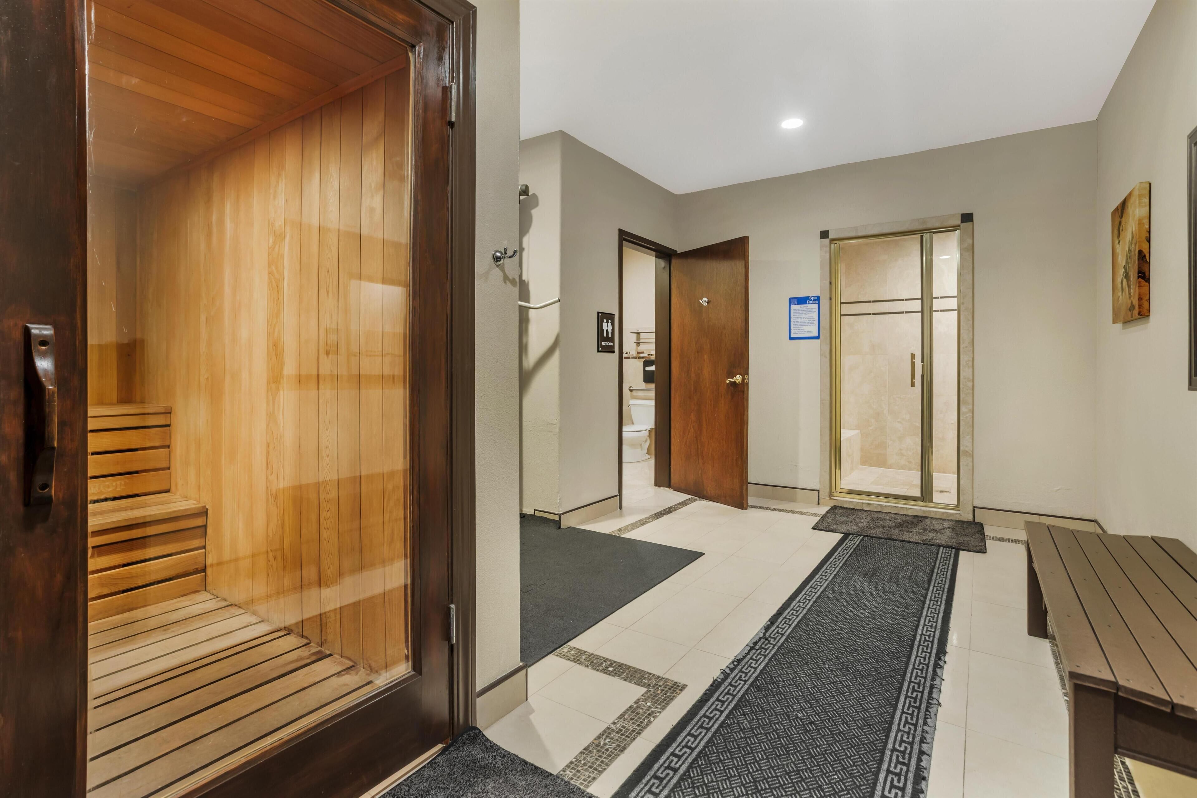 A hotel hallway with a sauna, a wooden bench, and a patterned rug.