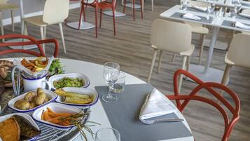 A dining area with tables set for meals, chairs, and a variety of dishes.