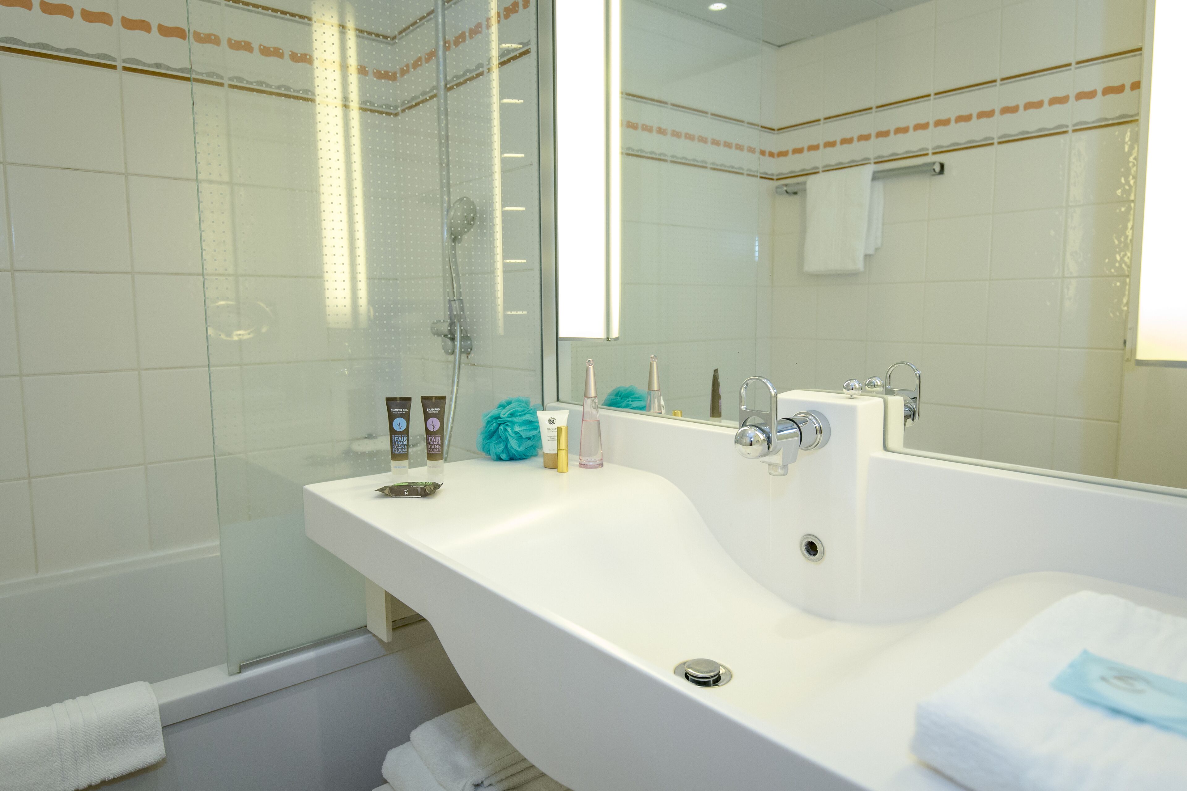 A modern bathroom with a large bathtub, a glass-enclosed shower, and a vanity with toiletries.