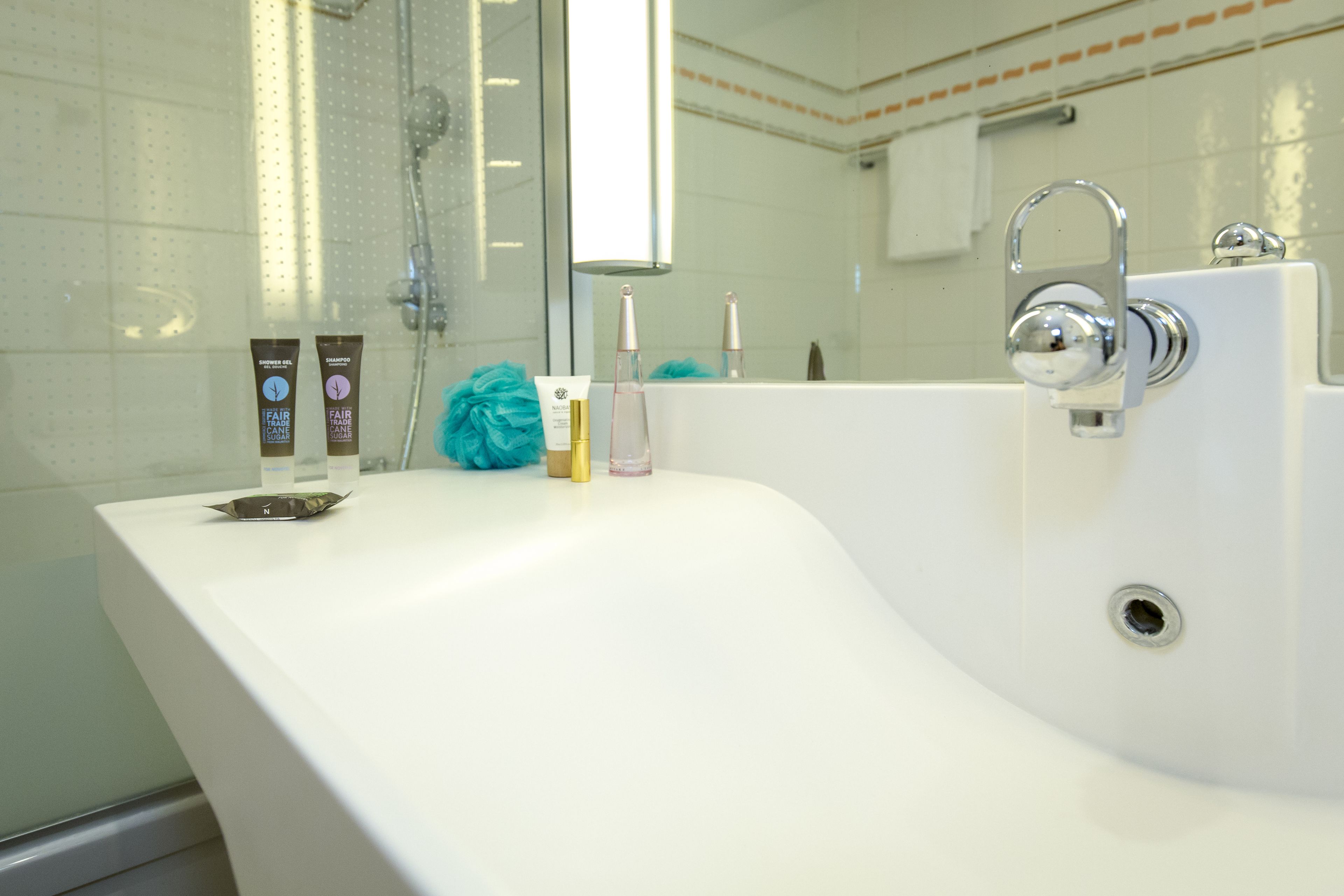 A bathroom with a white sink, a mirror, and toiletries.