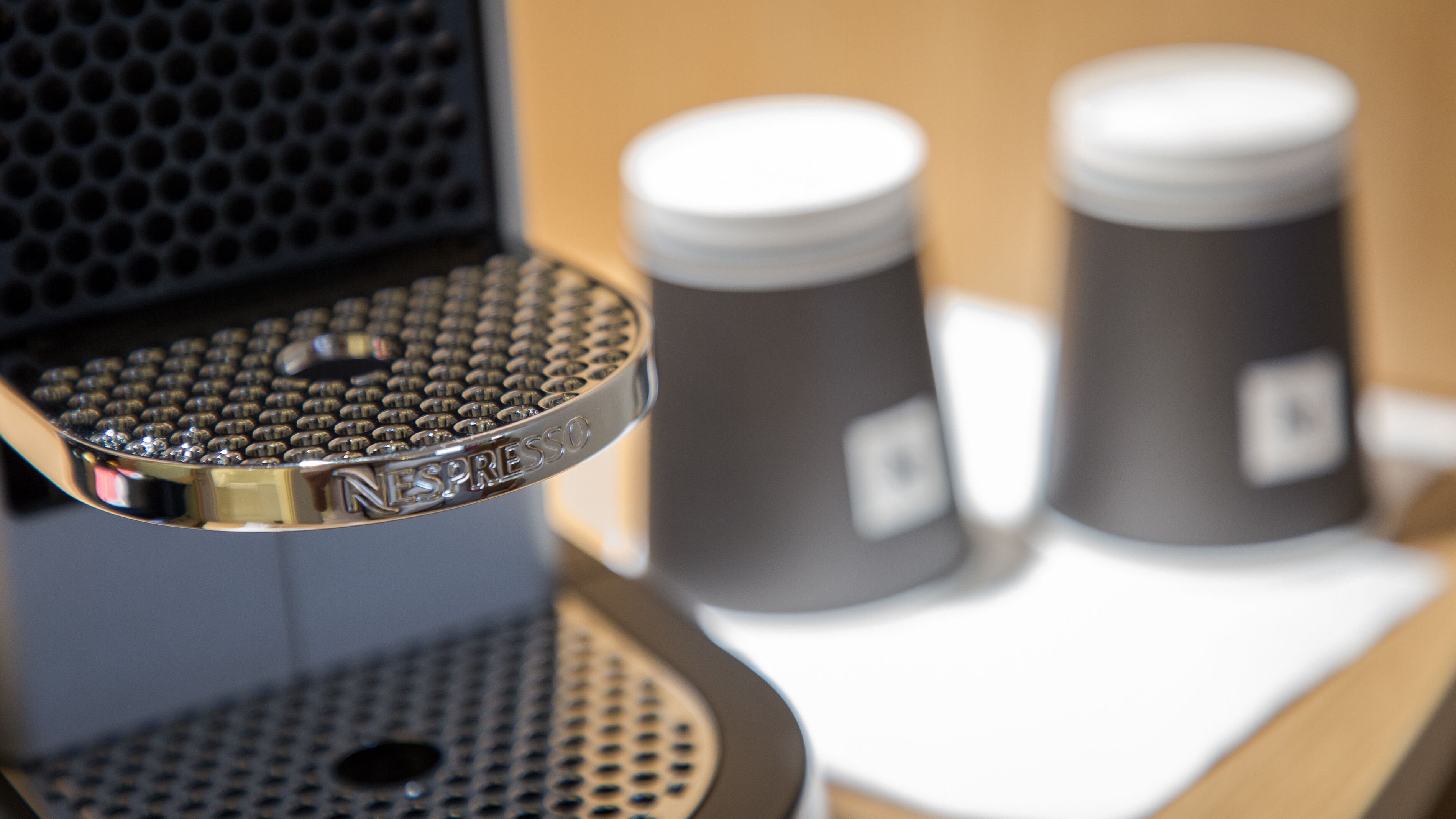 A coffee machine with a metal plate and two coffee cups on a table.