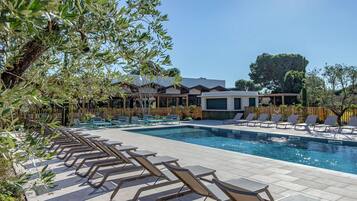 Zona de piscina con sillones de descanso, un edificio moderno y una valla de madera.