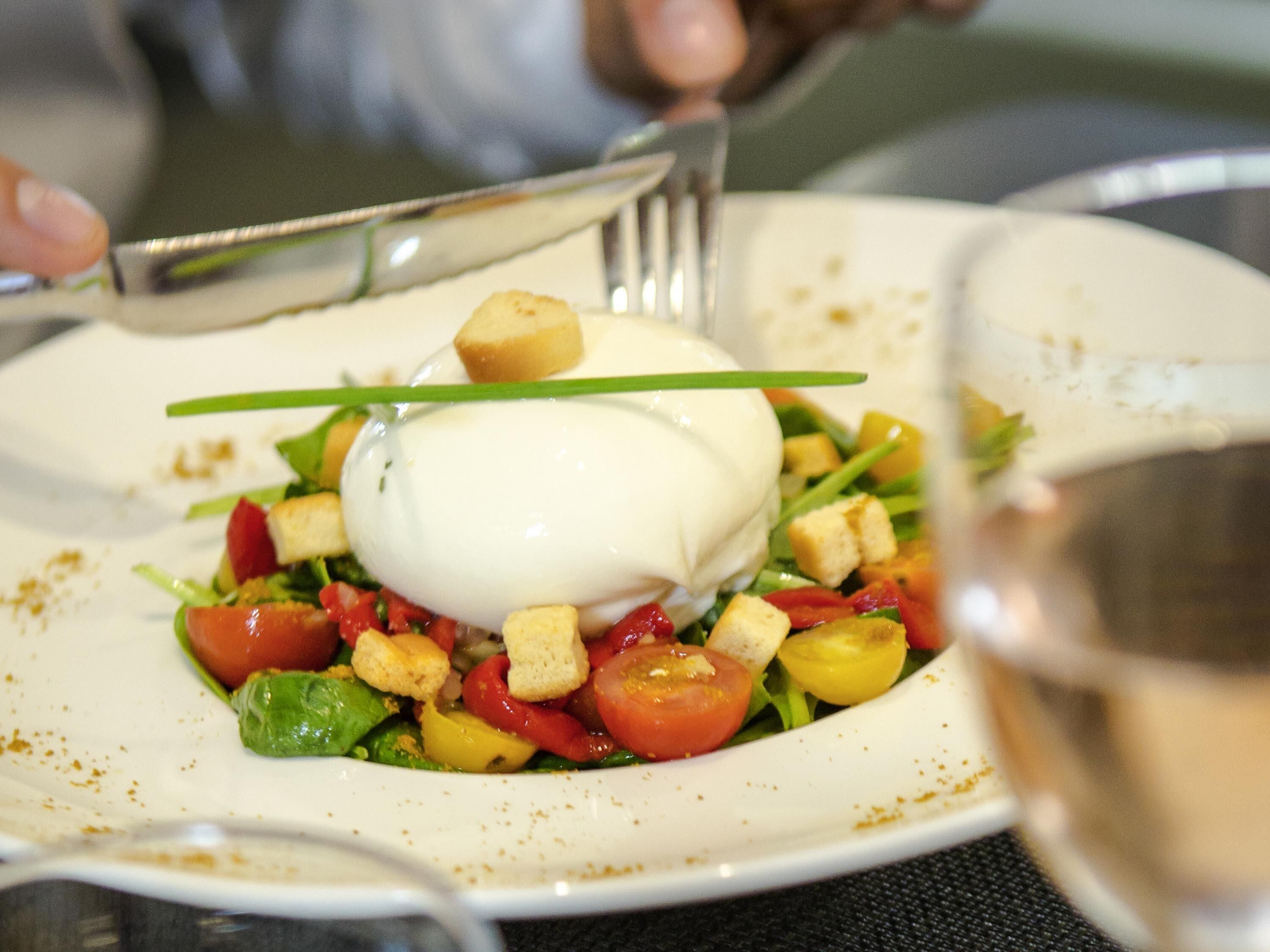 A plate of food with a poached egg, tomatoes, and croutons.