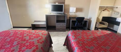 Une chambre d’hôtel avec deux lits, un bureau avec un ordinateur, une télévision et une chaise.