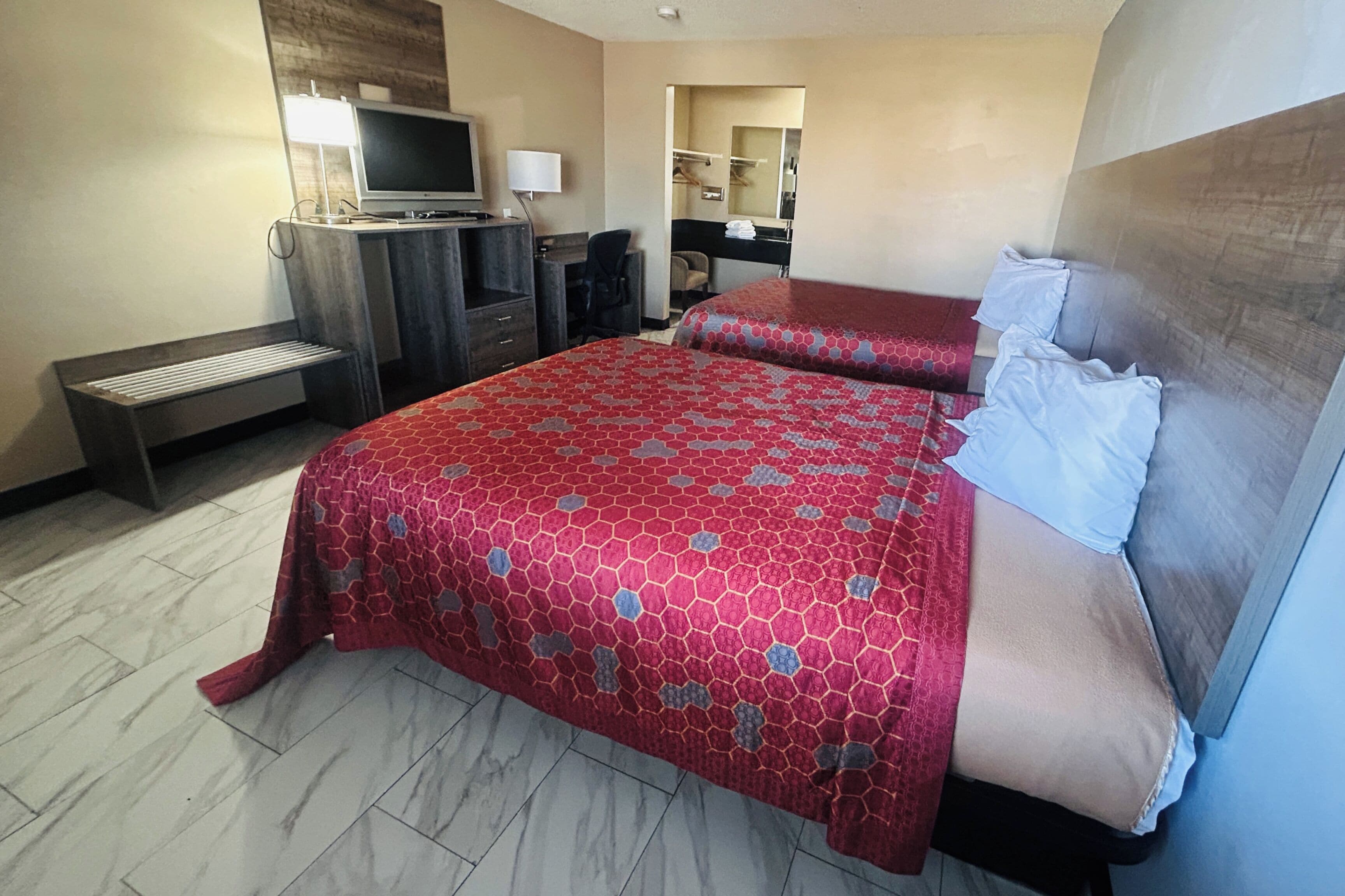 A hotel room with a bed, a desk, a TV, and a mirror.