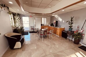 A modern interior with a dining area, a reception desk, and a kitchen. - Residential Suites Grain Valley by Hotel O I 70 (Grain Valley)