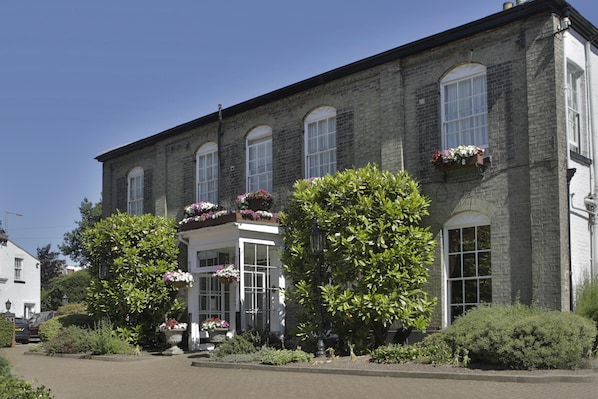 A two-story building with a symmetrical facade, large windows, and a central entrance with a white door.